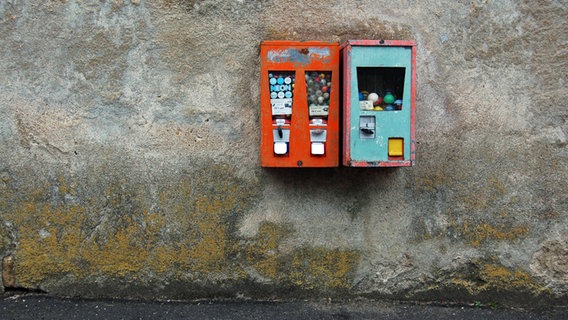 Zwei alte Kaugummiautomaten an einer schroffen grauen Wand. © Weigand / photocase.de Foto: Weigand