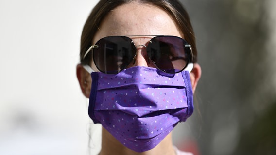 Eine junge Frau trägt eine Gesichtsmaske und eine Sonnenbrille. © picture alliance/dpa Themendienst Foto: Kirsten Neumann