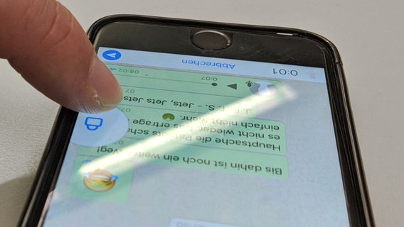 Ein Finger bedient ein Smartphone: Auf dem Bildschrim zieht die Hand das "Mikrofon"-Symbol im WhatsApp-Chat nach oben zum "Schloss"-Zeichen. © N-JOY Foto: N-JOY