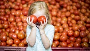 Ein Mädchen hält sich zwei Tomaten vor die Augen © imago/Westend61 